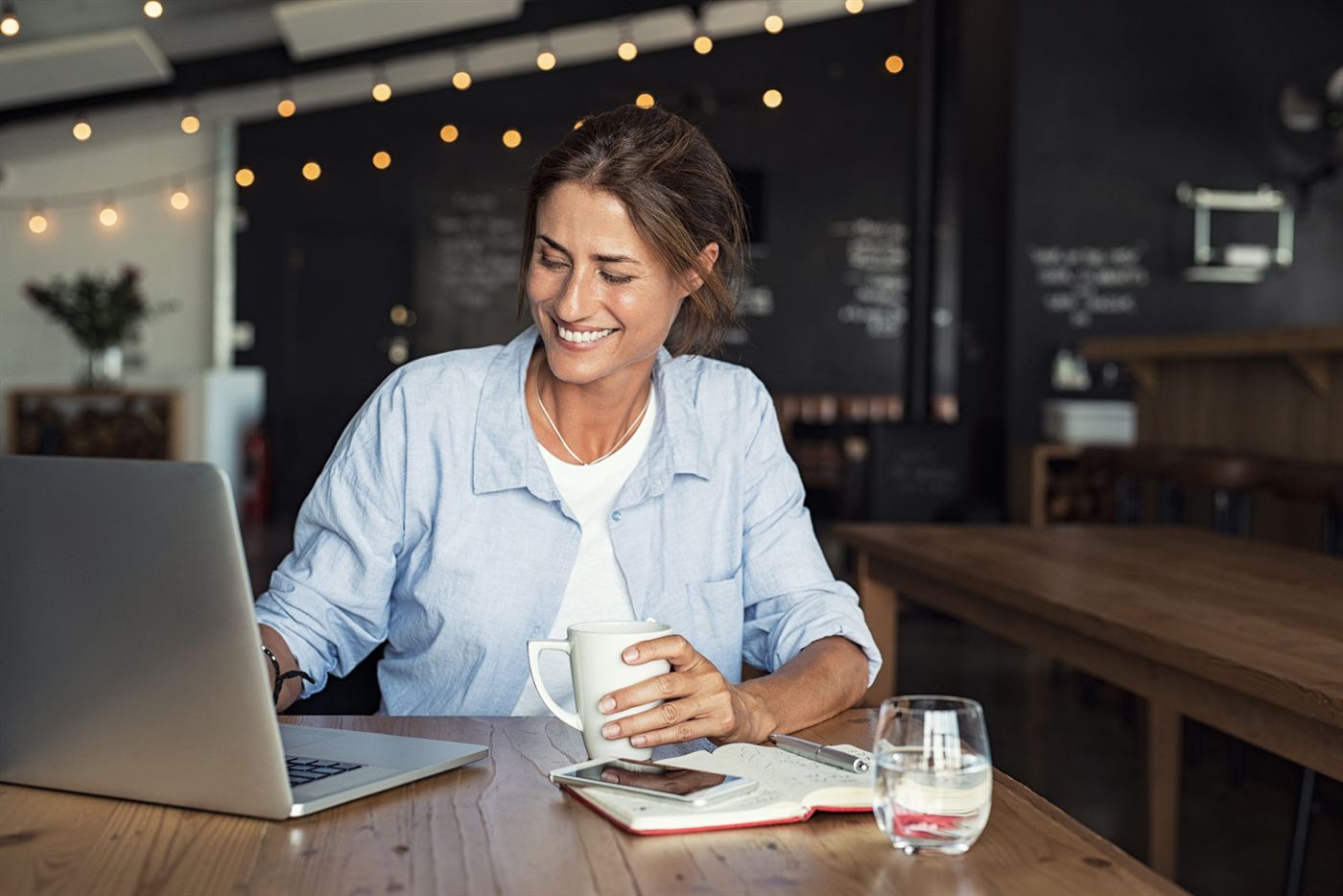Woman smiling at her laptop in a café