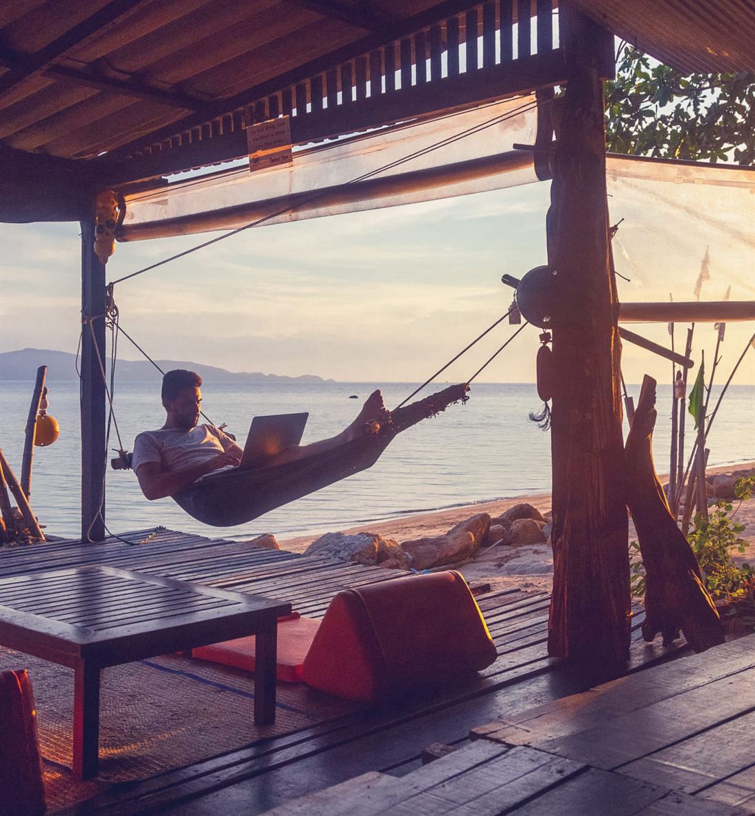 Working on a laptop from a hammock by the sea